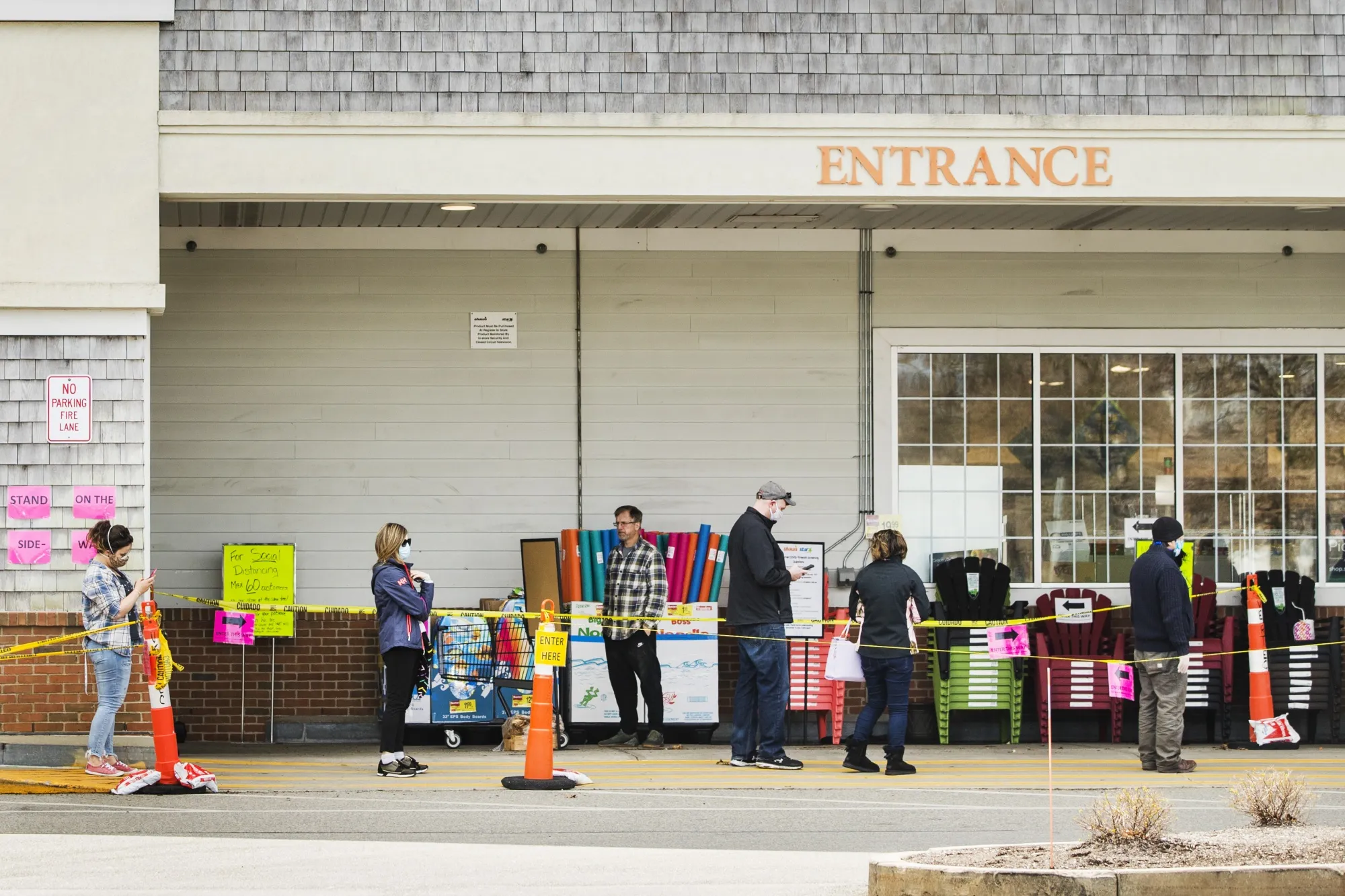 People wearing protective masks wait in line outside a store in Orleans, Massachusetts.