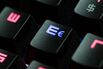 Computer keyboard glows red with blue illuminated euro symbol.