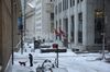 A pedestrian walks a dog as snow falls in the near the New York Stock Exchange (NYSE) in the Financial District of New York, U.S., on Thursday, Dec. 17, 2020. Winter Storm Gail pounded the city as temperatures dropped to 27 degrees with frigid sustained winds up to 35 mph, making dining outdoors unbearable amid the Covid-19 pandemic that has already crippled the restaurant industry.