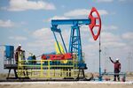 Workers perform maintenance on an oil pumping unit, also known as a "nodding donkey", at an oilfield operated by Embamunaigas, a unit of KazMunaiGas Exploration Production, in Akkystau village, near Atyrau, Kazakhstan, on Saturday, July 4, 2015. The majority Muslim country is central Asia's biggest oil producer. Photographer: Bloomberg/Bloomberg