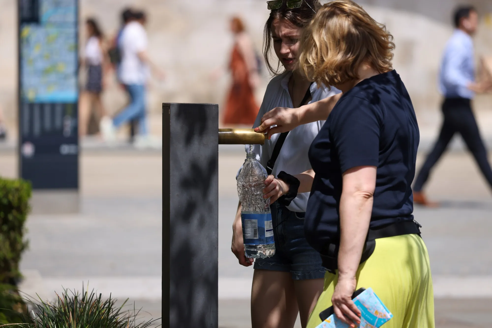 Pedestrians fill a bottle with water in London on June 17.