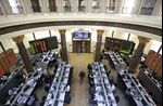 Financial traders work beneath digital boards displaying financial data in the trading hall of the Egyptian stock exchange in Cairo.