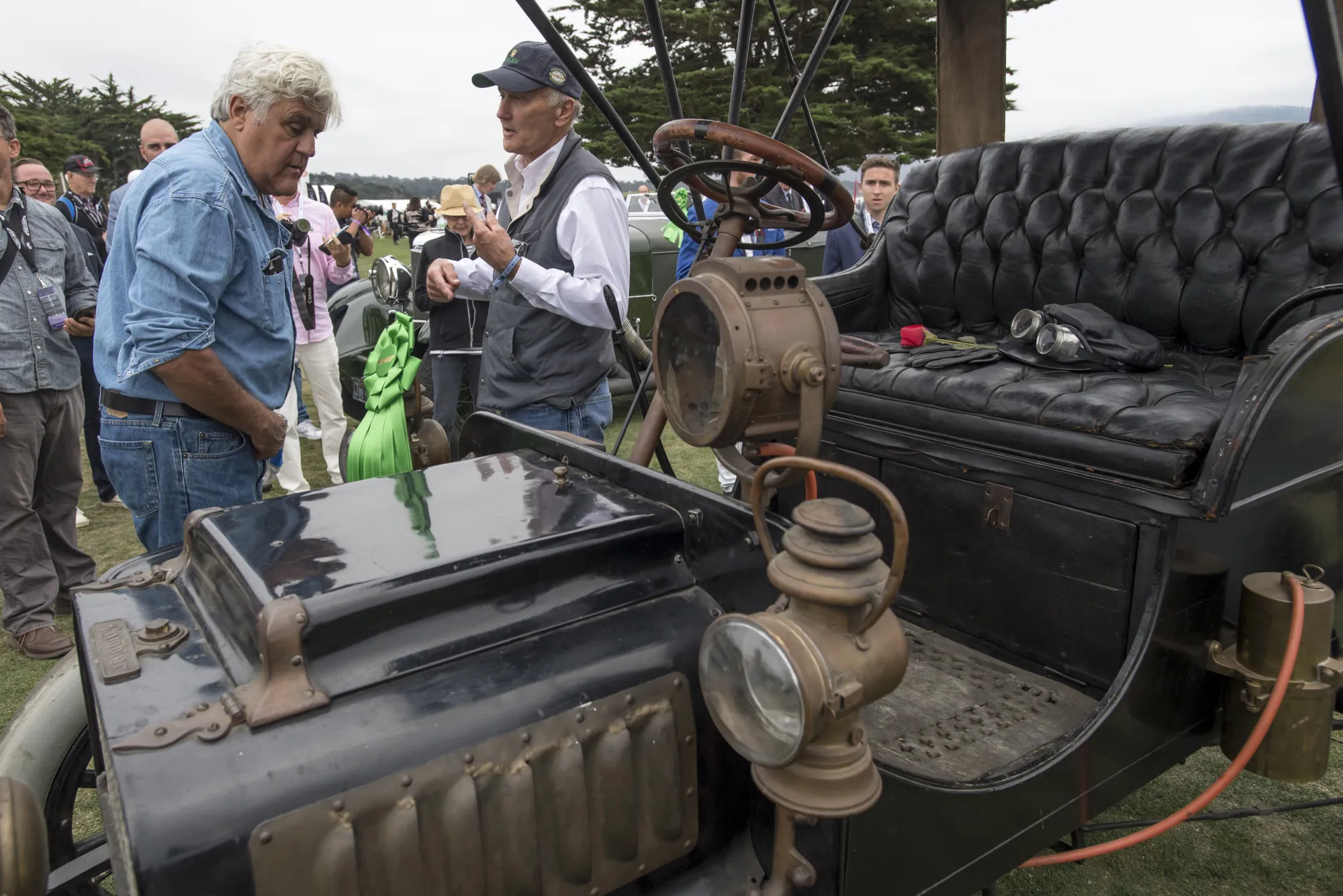 Jay Leno looks at a 1904 Rambler Model H Rear Entrance Tonneau vehicle on display during the 2017 Pebble Beach Concours d'Elegance.