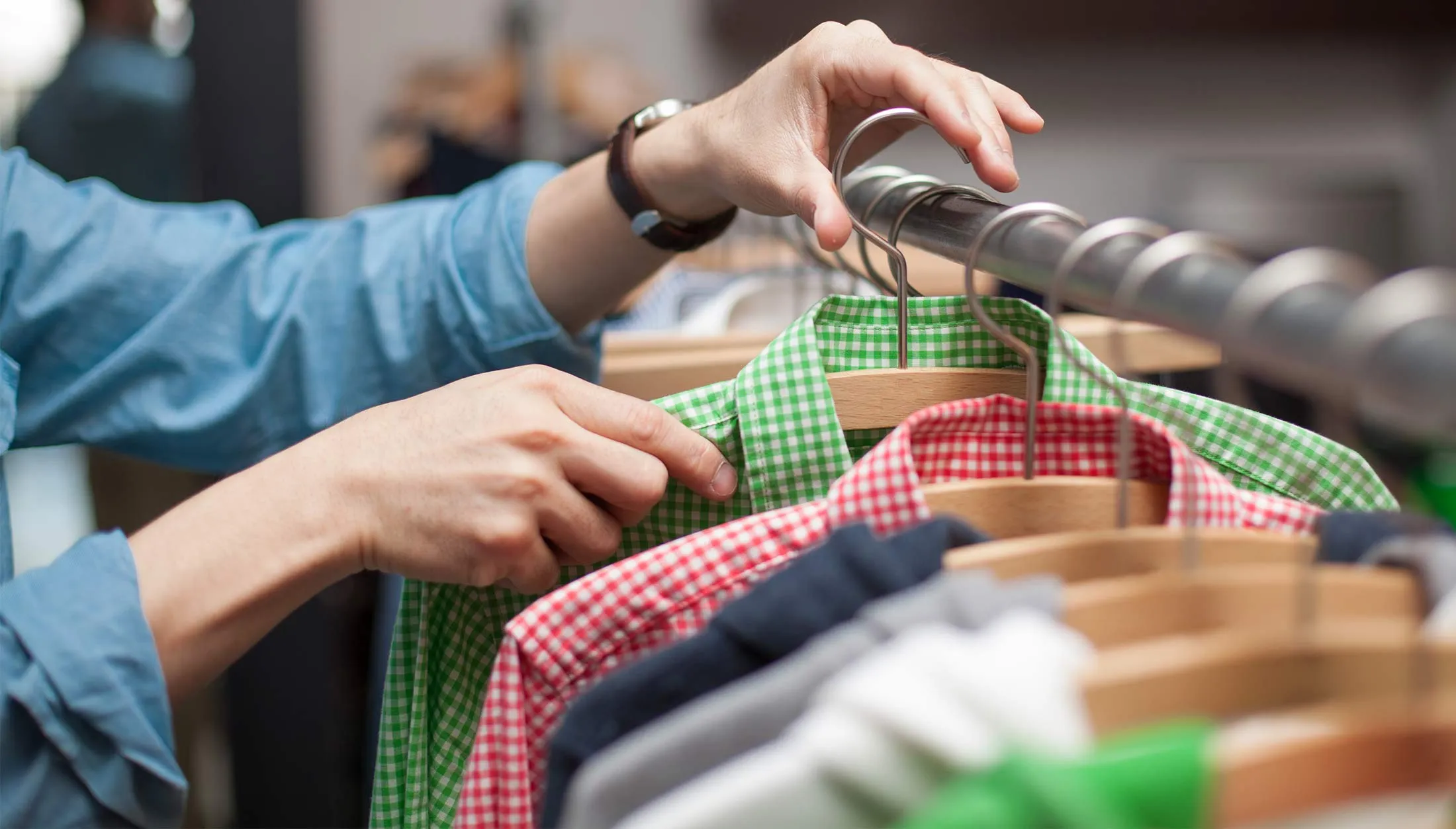 A hand removing or placing clothing on a rack