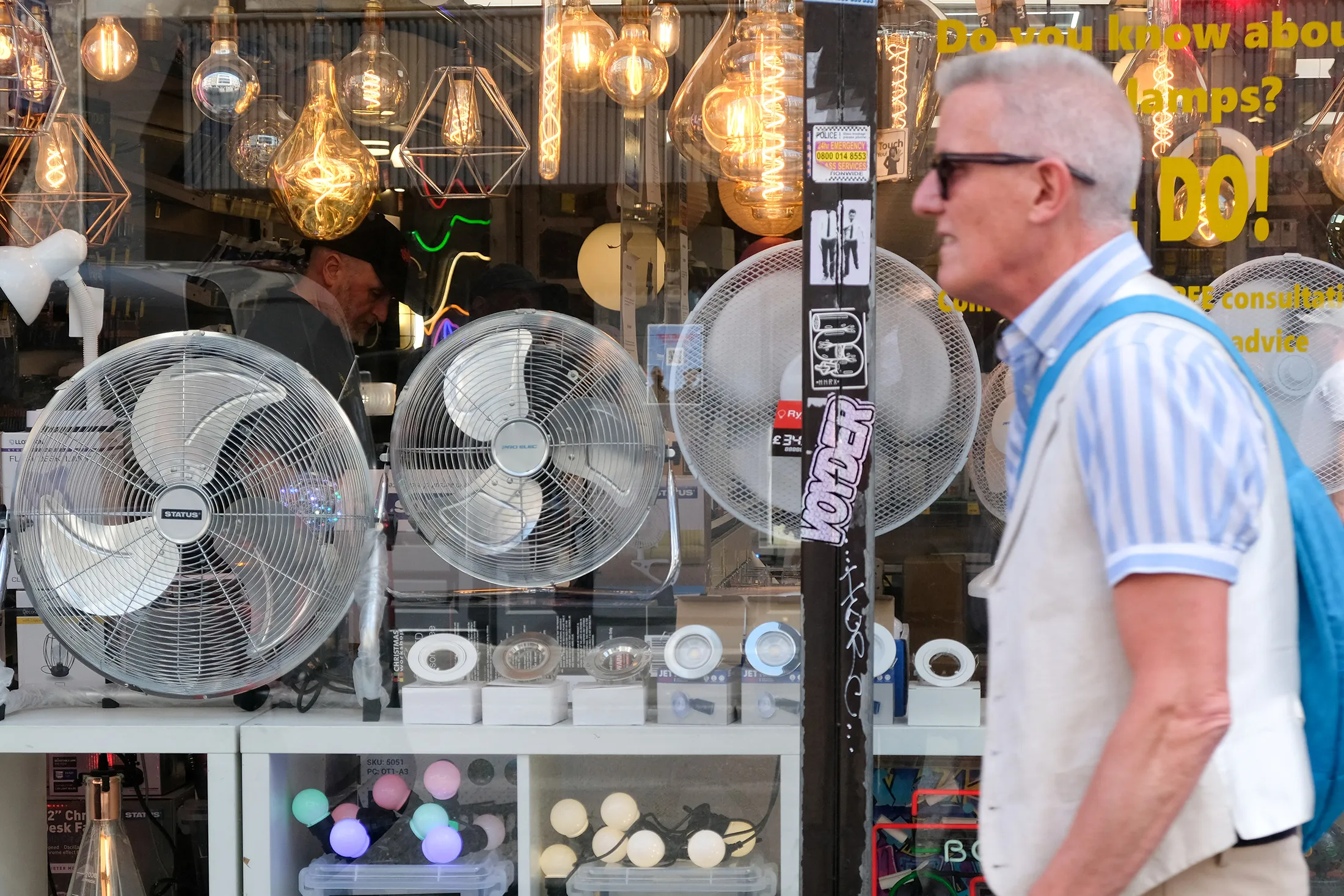 A pedestrians walks past fans for sale during a heatwave in London, UK, on July 15.