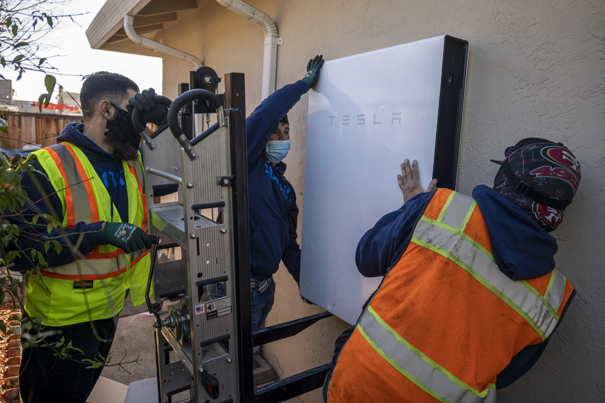 Contractors mount a Tesla Powerwall battery unit at a home in San Jose, California.