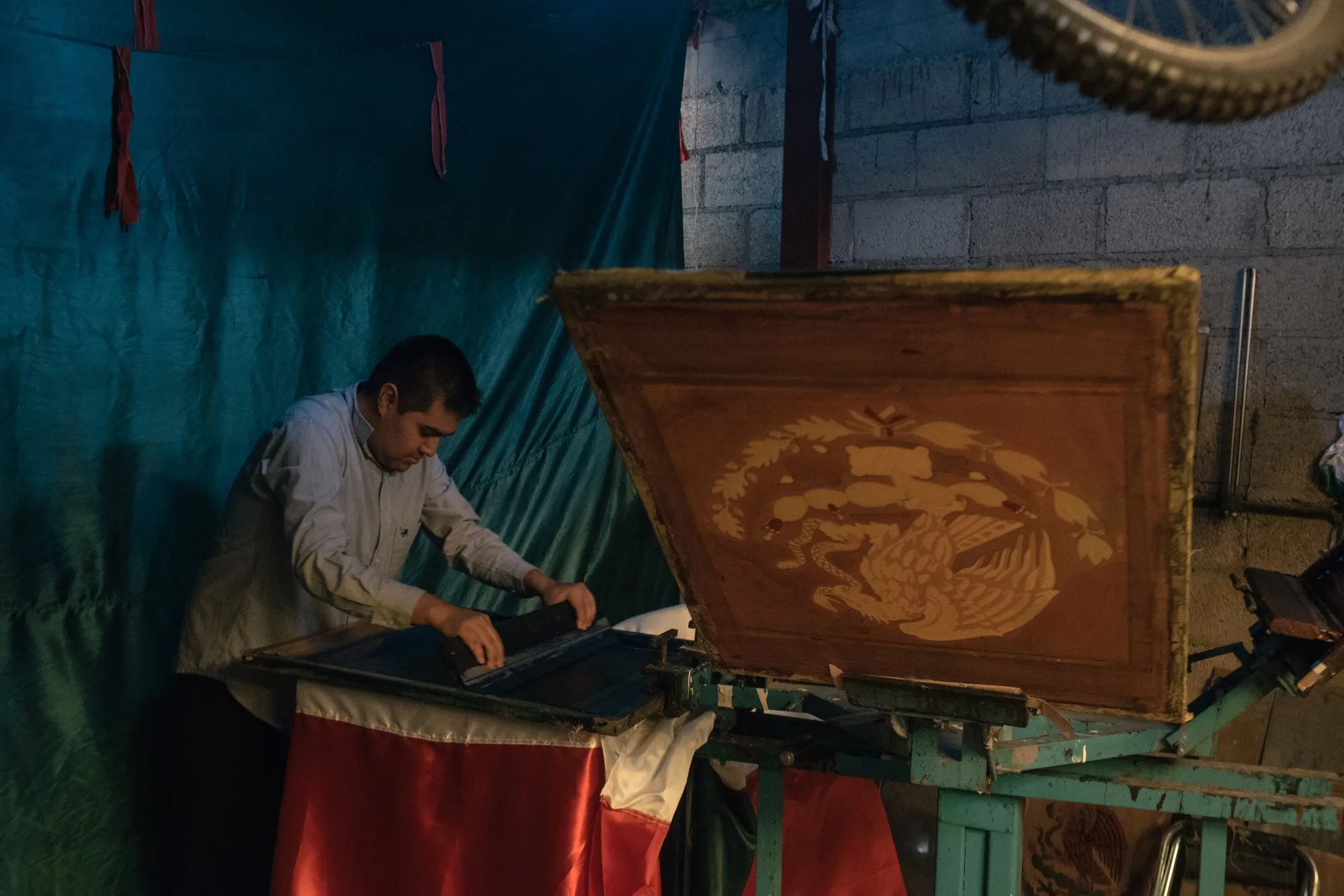 A worker spreads ink onto a screen printing press at a flag manufacturing facility in Toluca, Mexico.