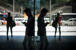 A man is reflected in a window while using a smart phone in Hong Kong, China.