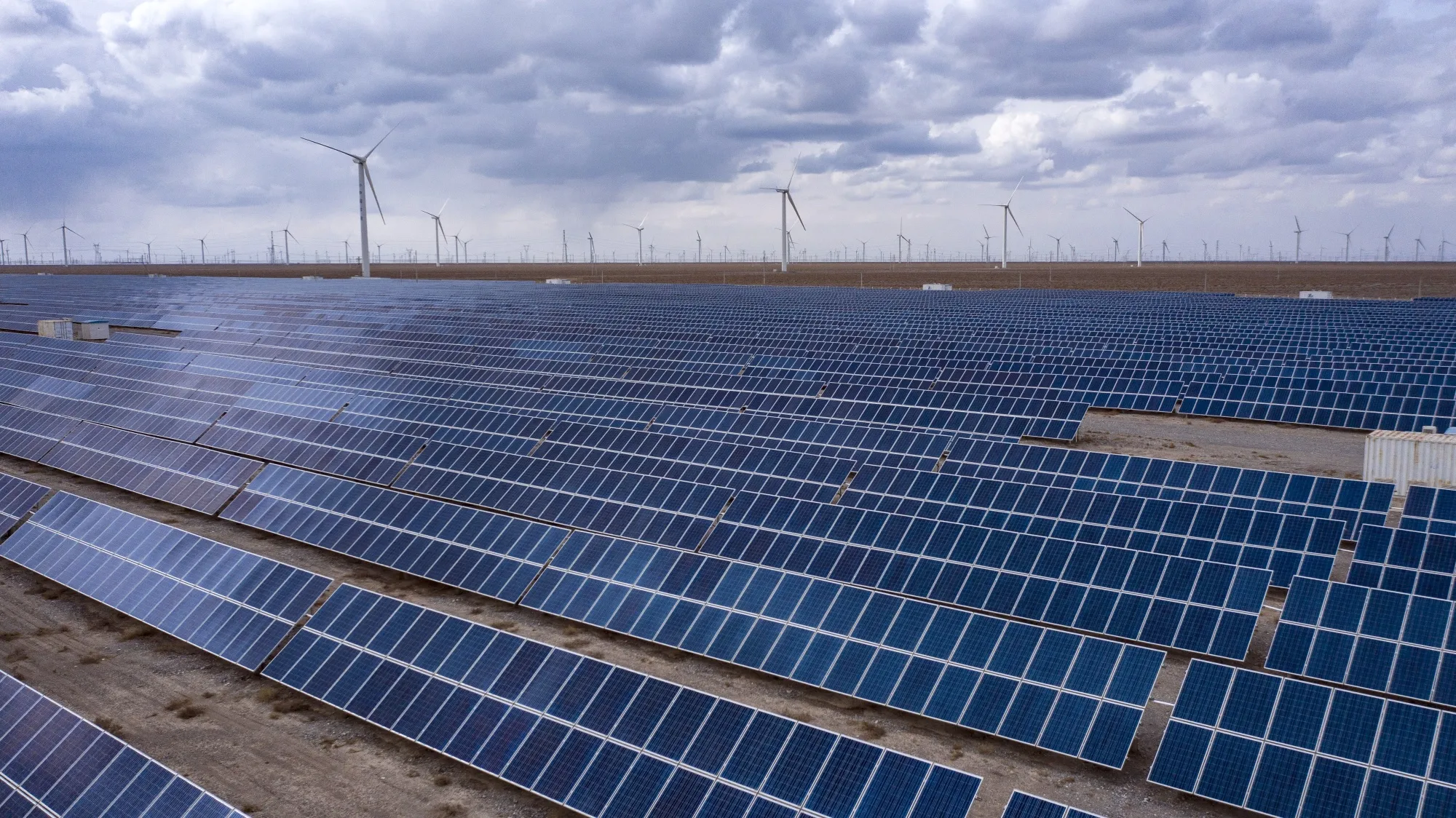 Солнечные панели и ветряные турбины недалеко от Юмэня, провинция Ганьсу, Китай.