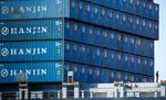 A worker stands as containers sit stacked on the Hanjin Gdynia cargo ship berthed at the Port of Long Beach in Long Beach, Calif.