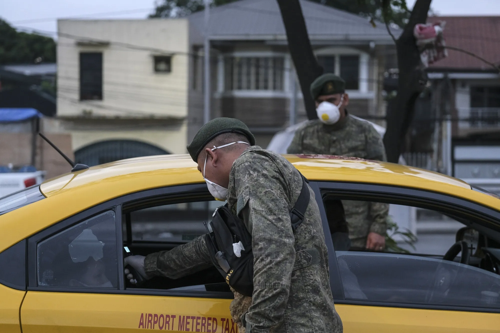 A member of the Philippine Army takes the temperature of a passenger of a taxi, traveling into Metro Manila.