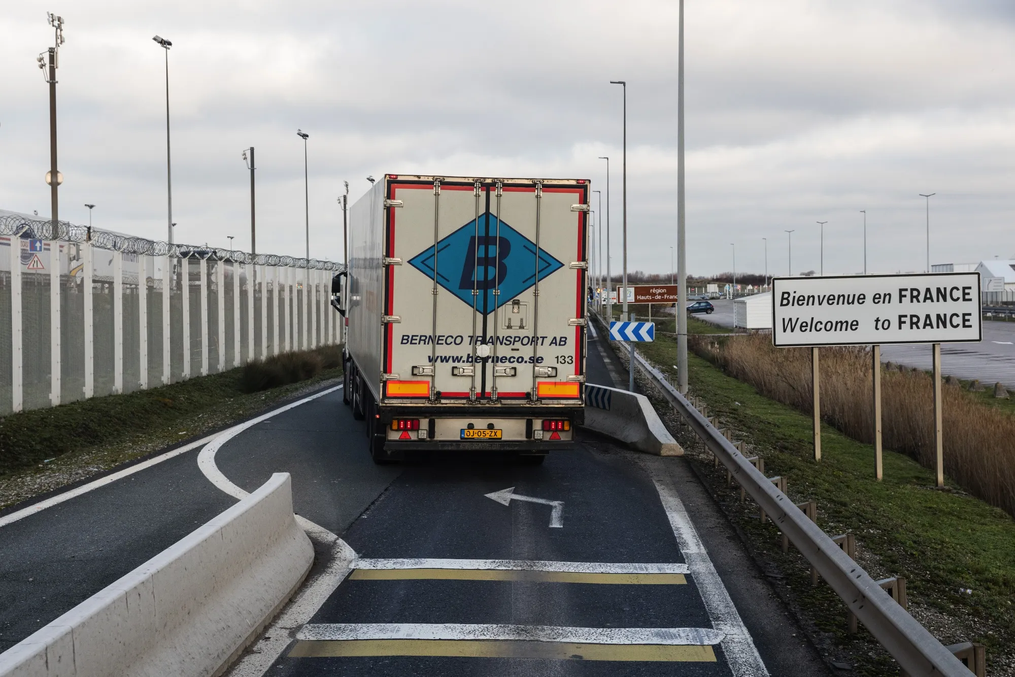 A haulage truck passes a 'Welcome to France' sign on an access road near the Eurotunnel terminal in Calais, France.
