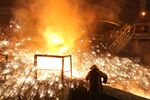 A worker supervises the flow of hot liquid metal as it flows from the blast furnace during a smelting&nbsp;in Novokuznetsk, Russia.
