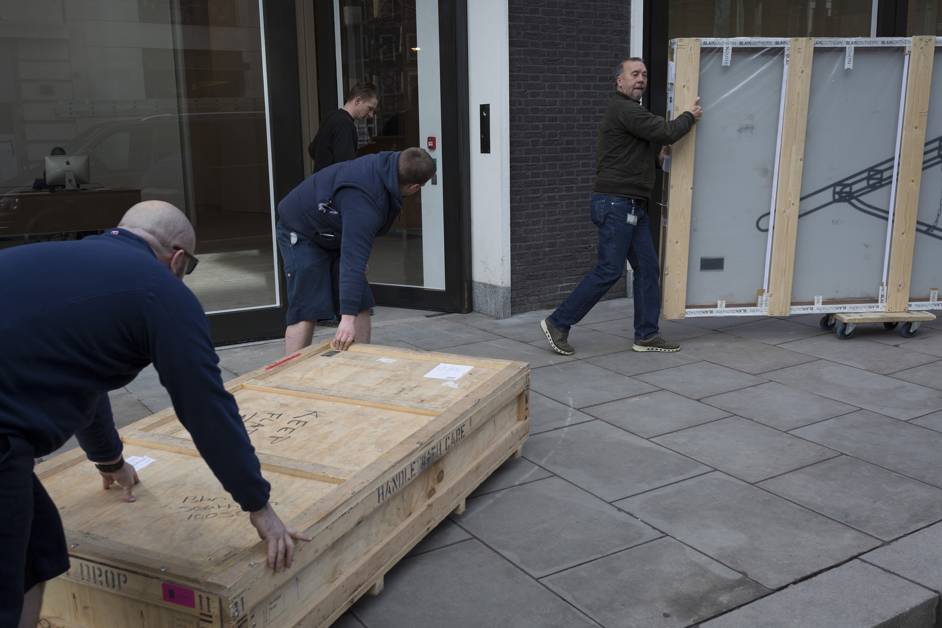Deliverymen move a flat crate containing artworks in London.
