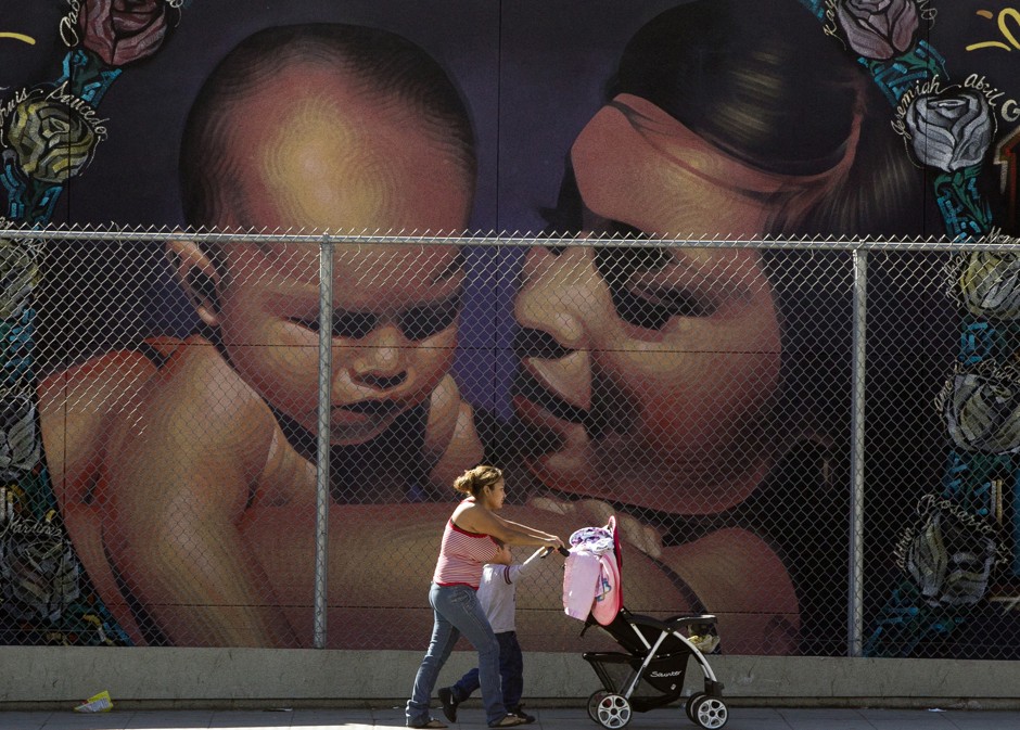 A Hispanic mother walks with a stroller and a young child in California. 