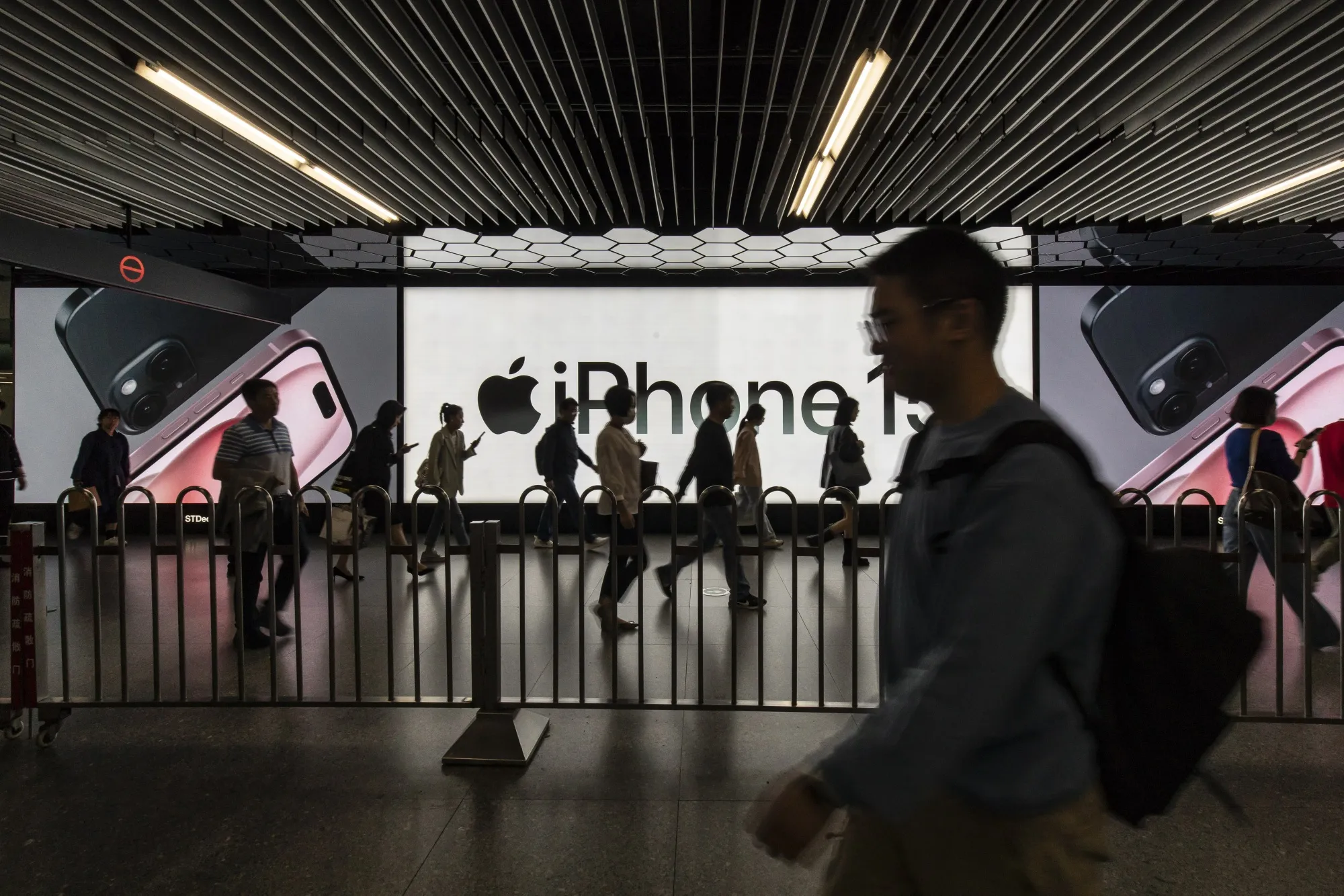 Morning commuters pass an advertisement for the Apple iPhone 15 at a subway station.