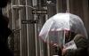 A pedestrian carries an umbrella while walking along Wall Street near the New York Stock Exchange.