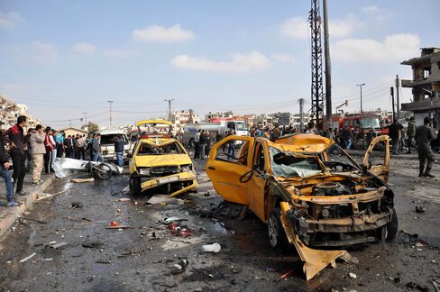 Syrians gather at the site of a double car bomb attack in the Al-Zahraa neighbourhood in Homs on Sunday.