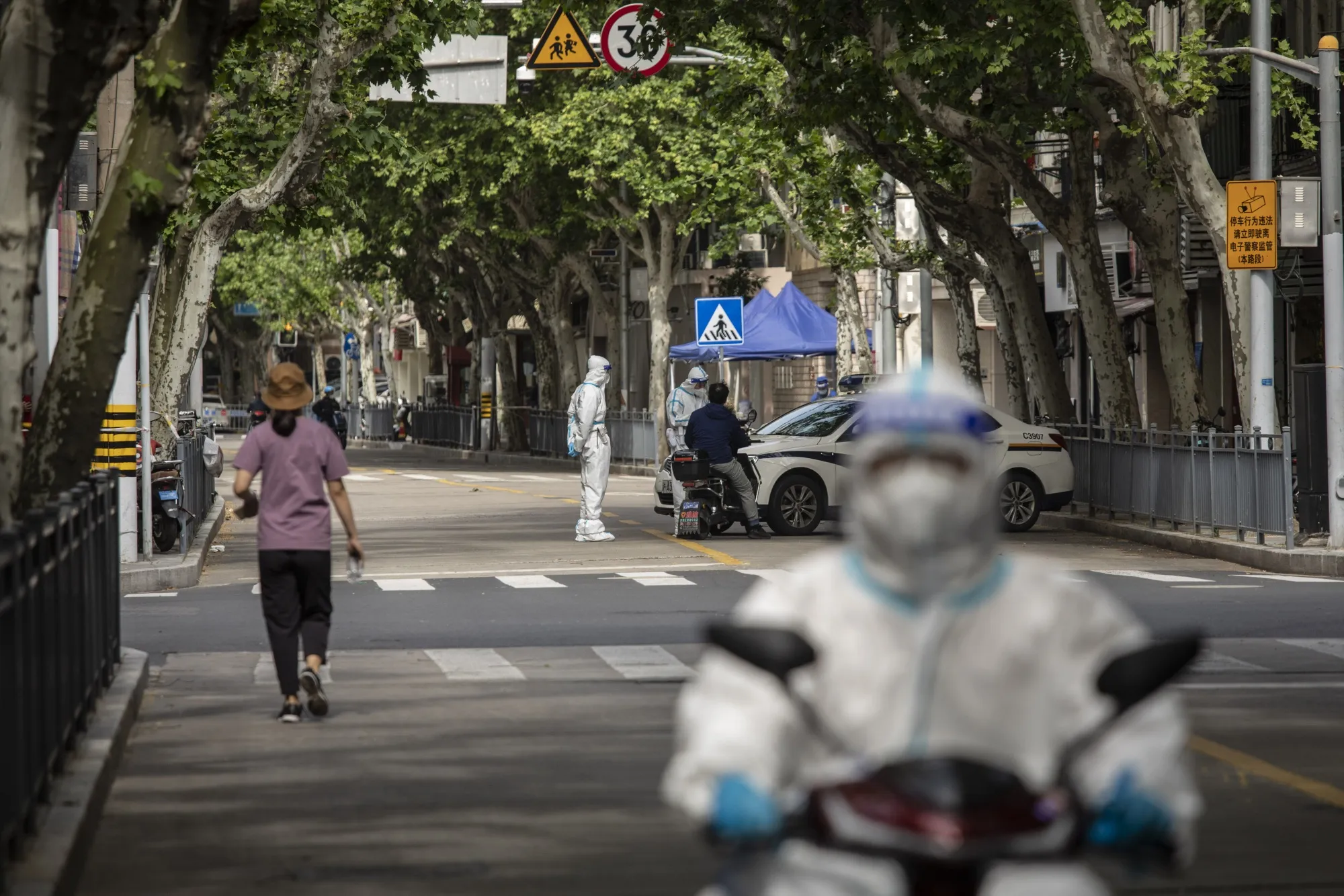 Police officers in personal protective equipment (PPE) check commuters' documents during a lockdown in Shanghai, China, on Thursday, April 28, 2022.