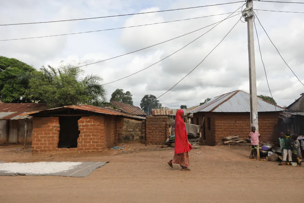 A woman walks under the transmission lines of a Husk Power mini-grid in Rukubi, Nigeria.