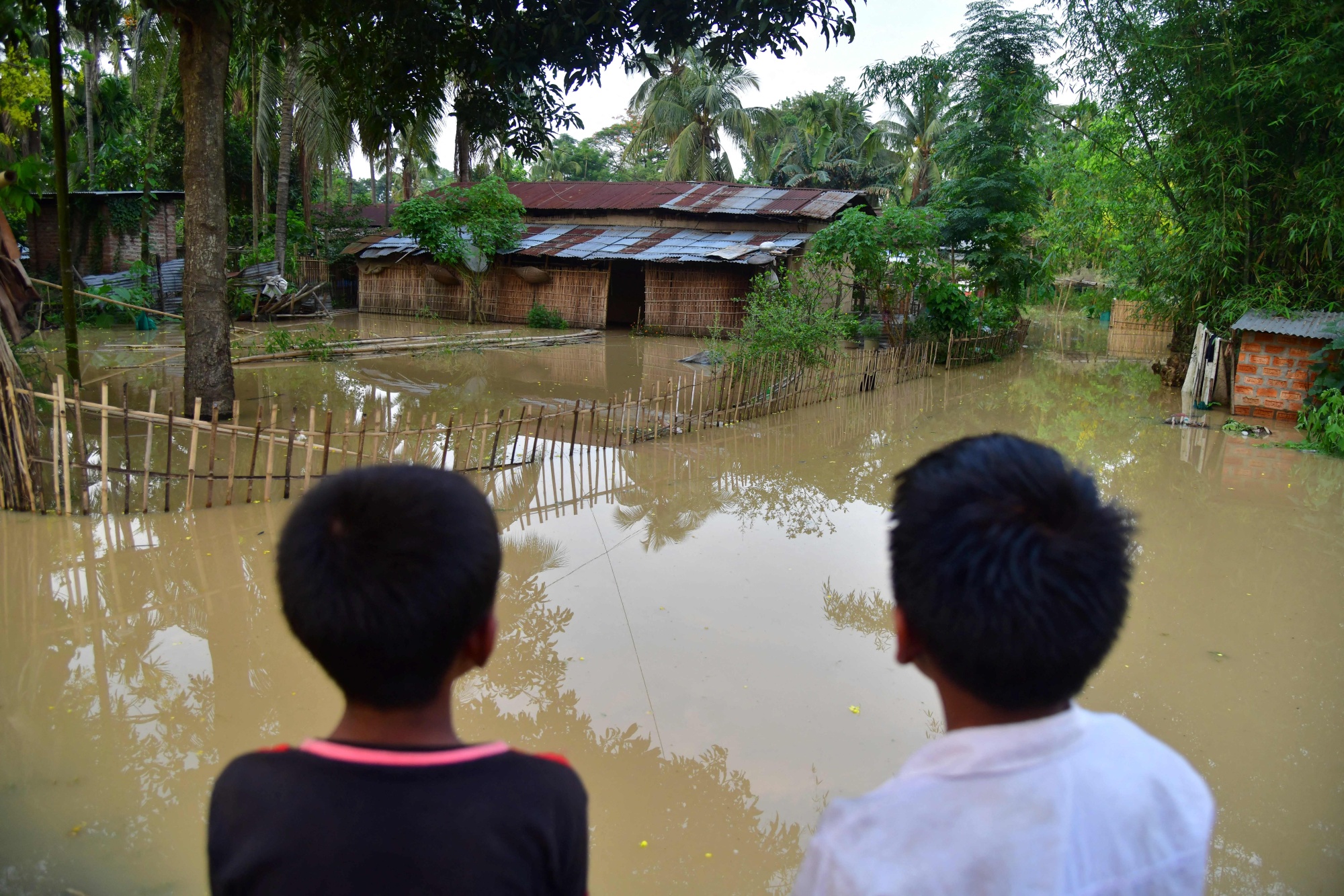 Children look at their partially submerged house after heavy rains in Morigaon district of India's Assam state on May 23.