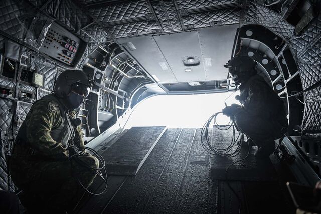 Two military personnel on a CH-47 Chinook helicopter flying near Tanegashima.