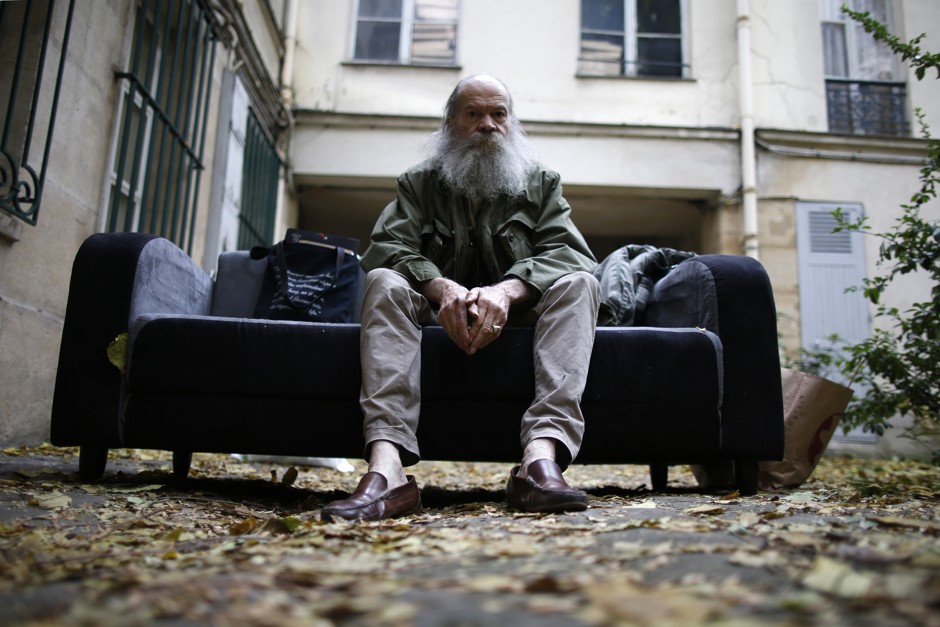 Alain Le Yaouanc, a 74-year-old Parisian artist, sits on a sofa in the courtyard of his building after he was evicted from his apartment and studio in October. New policies in the French capital seek to spur more affordable housing opportunities in gentrifying areas of the city. 