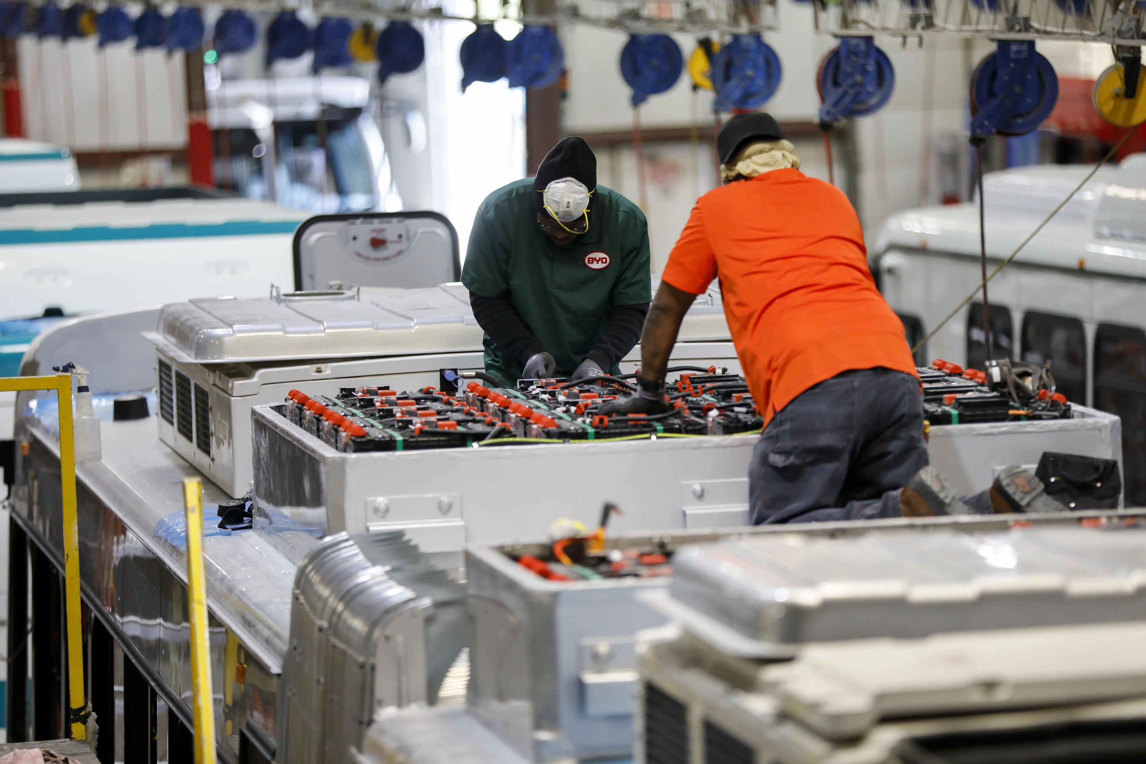 Employees work on the roof of an electric bus at the BYD Coach and Bus factory in Lancaster, California, U.S., on Thursday, Oct. 5, 2017.&nbsp;