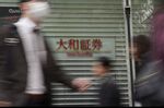 Pedestrians walk past the Daiwa Securities Co. headquarters in Tokyo, Japan.