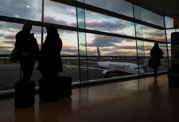 Passengers stand by a window as they wait to board a Ryanair Holdings Plc aircraft at Dublin Airport, operated by Dublin Airport Authority, in Dublin, Ireland, on Friday, Nov. 25, 2016. Ryanair provides low fare passenger airline services to destinations in Europe. Photographer: Chris Ratcliffe/Bloomberg