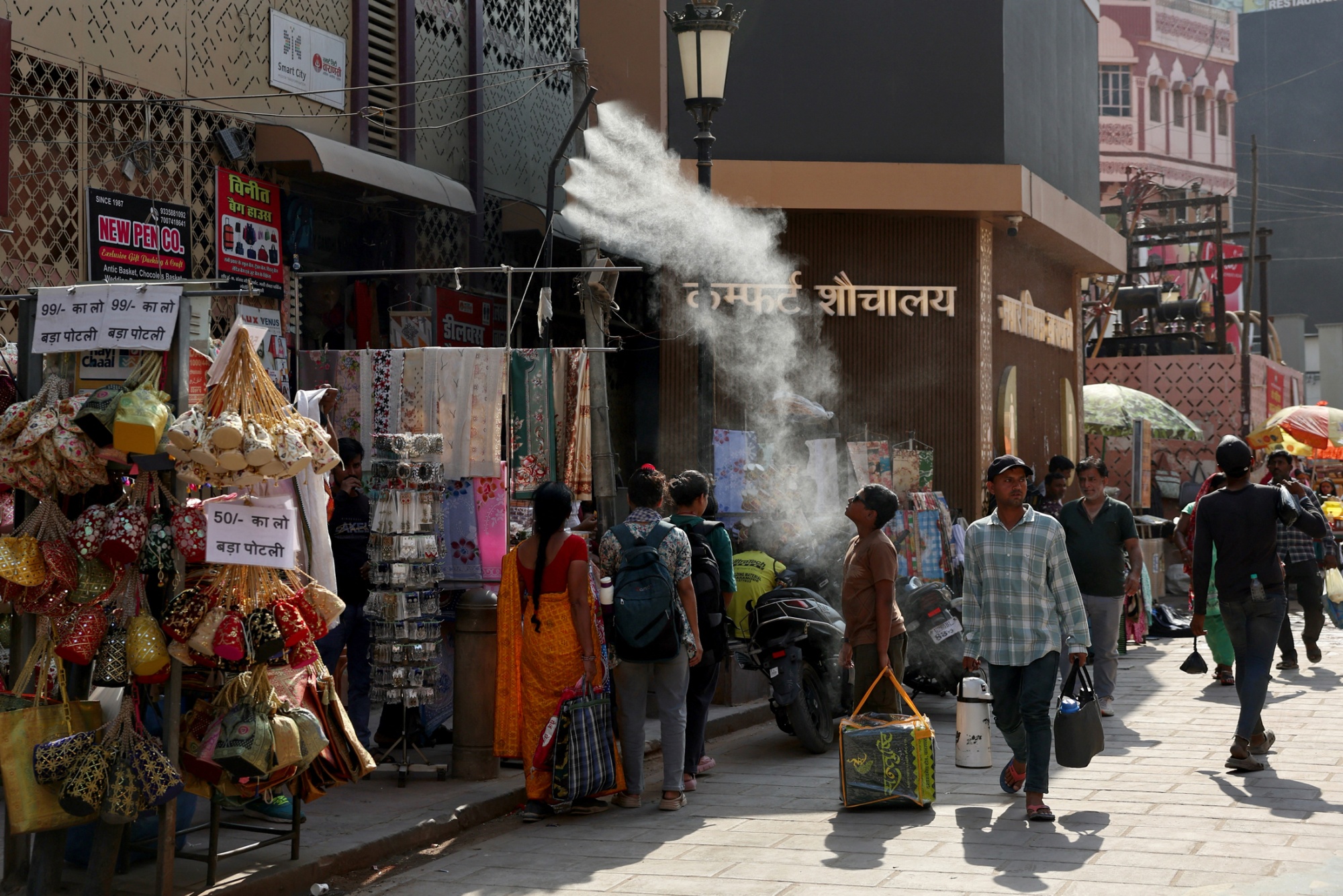 Pedestrians use a water mist sprayer along a street in Varanasi, India, on April 24. Photographer: Niharika Kulkarni/Getty Images
