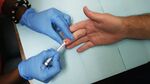 A health educator uses a syringe to take a drop of blood from a man's finger on Sept. 27, 2012, in Washington.
