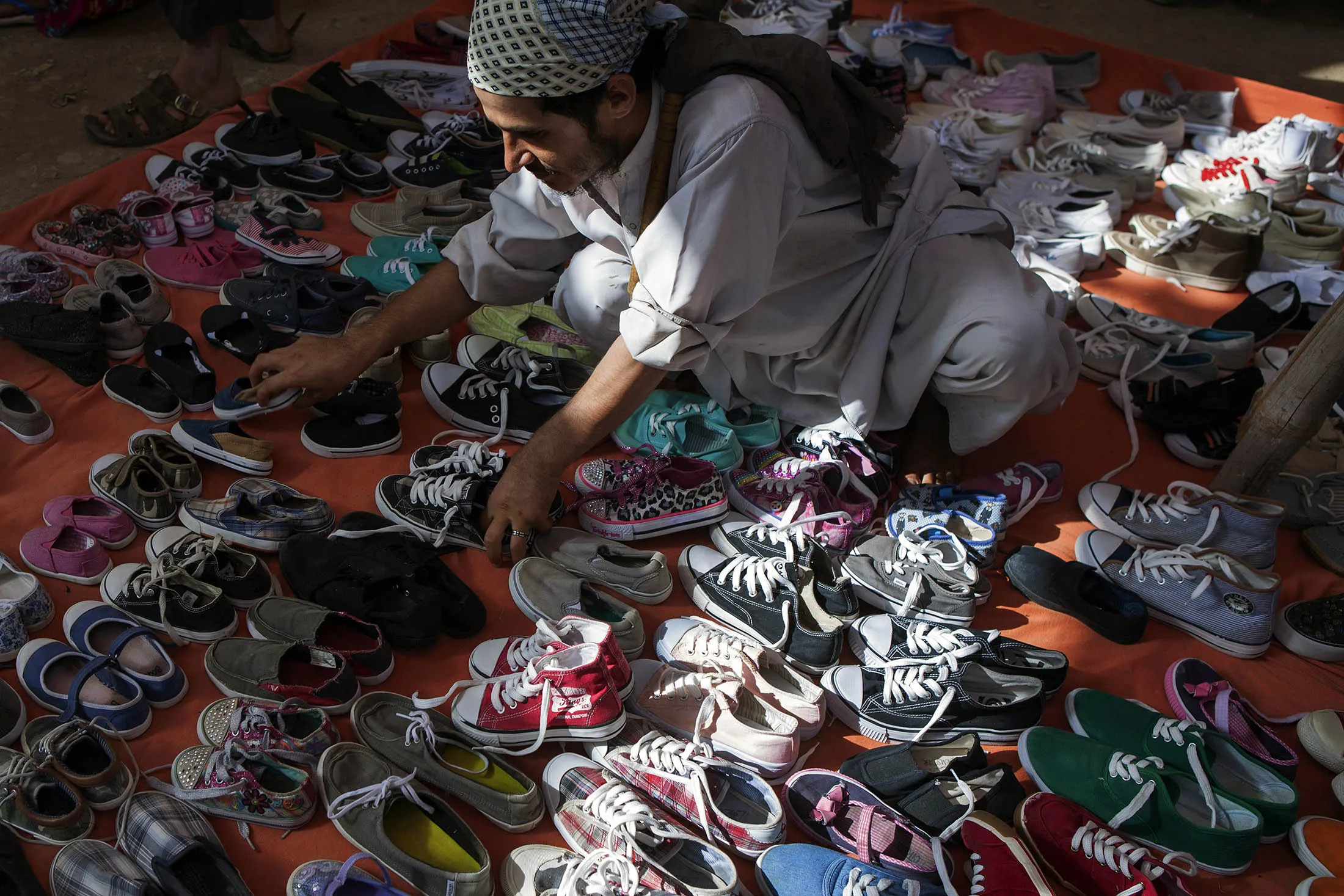 A vendor arranges a display of shoes in a market in Karachi, Pakistan, on Sunday, May 31, 2015.
