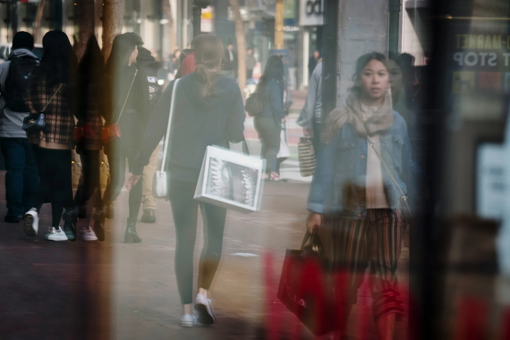 Pedestrians are reflected in a store window on Market Street in San Francisco on Jan. 3, 2019.