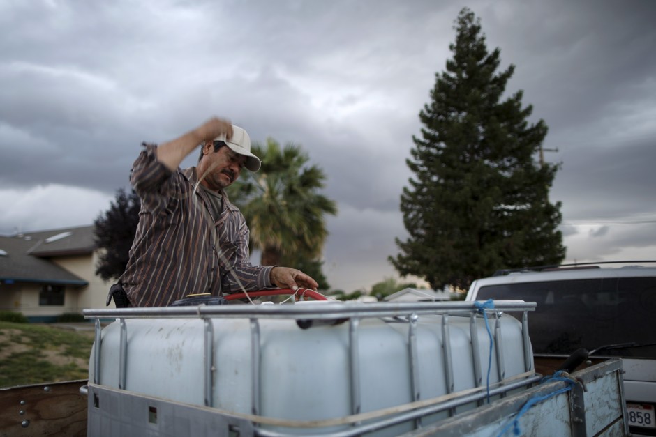 A farmworker fills a water tank in East Porterville, California. 