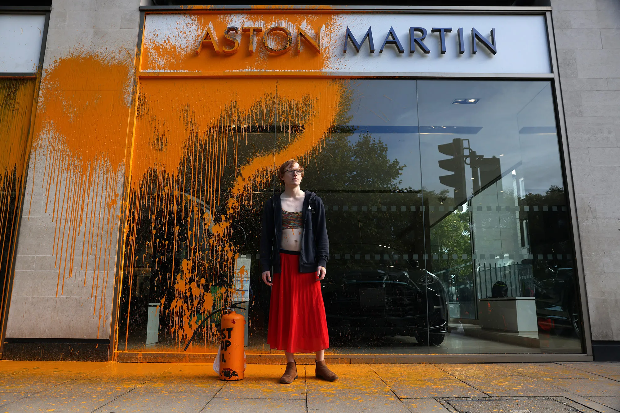 A Just Stop Oil demonstrator sprays an orange substance on an Aston Martin store in Mayfair, on Oct.&nbsp;16.&nbsp;