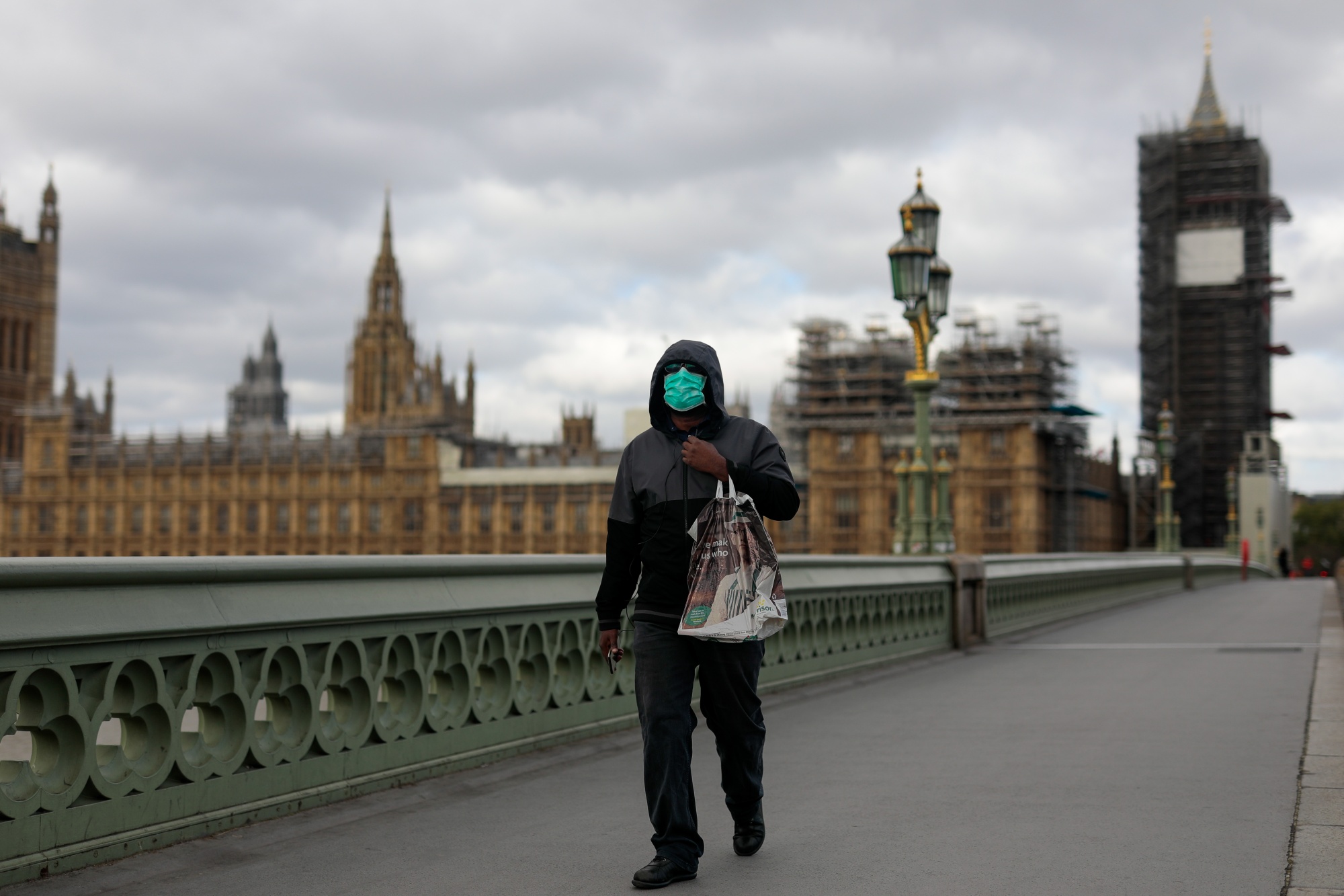 A commuter wearing a protective face mask crosses Westminster Bridge in view of the Houses of Parliament and Elizabeth Tower in London, U.K., on&nbsp;May 11.