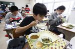 Students eat lunch at their desks at an elementary school in Chiba, Japan.