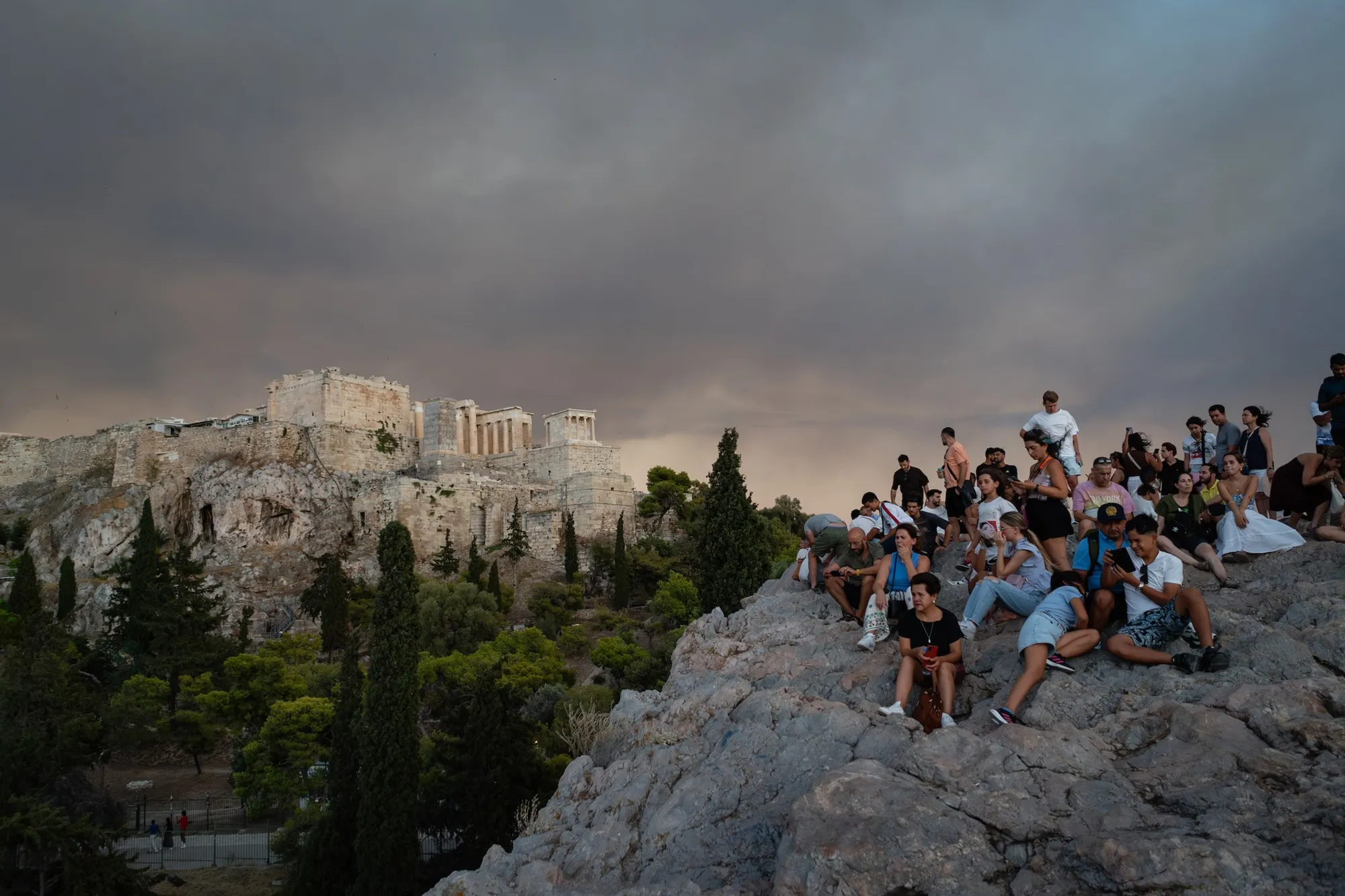 Tourists watch as smoke from wildfires fills the sky above the Acropolis citadel in Athens.