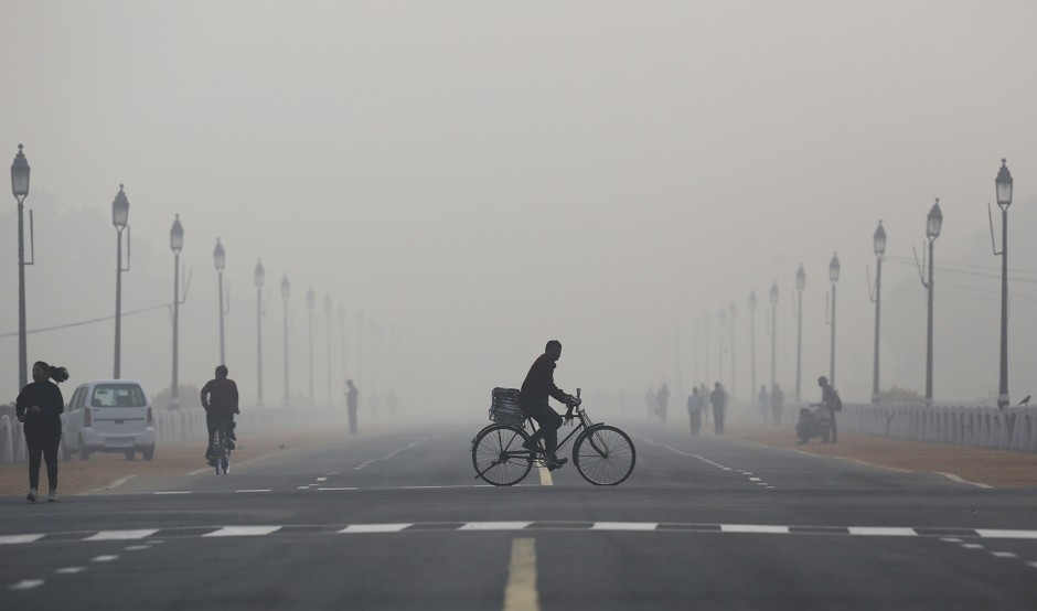 A newspaper vendor bikes on a smoggy morning in New Delhi on December 1, 2015.