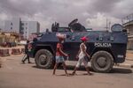 Pedestrians walk past Angola police enforcing a lockdown in Luanda, Angola, in April.