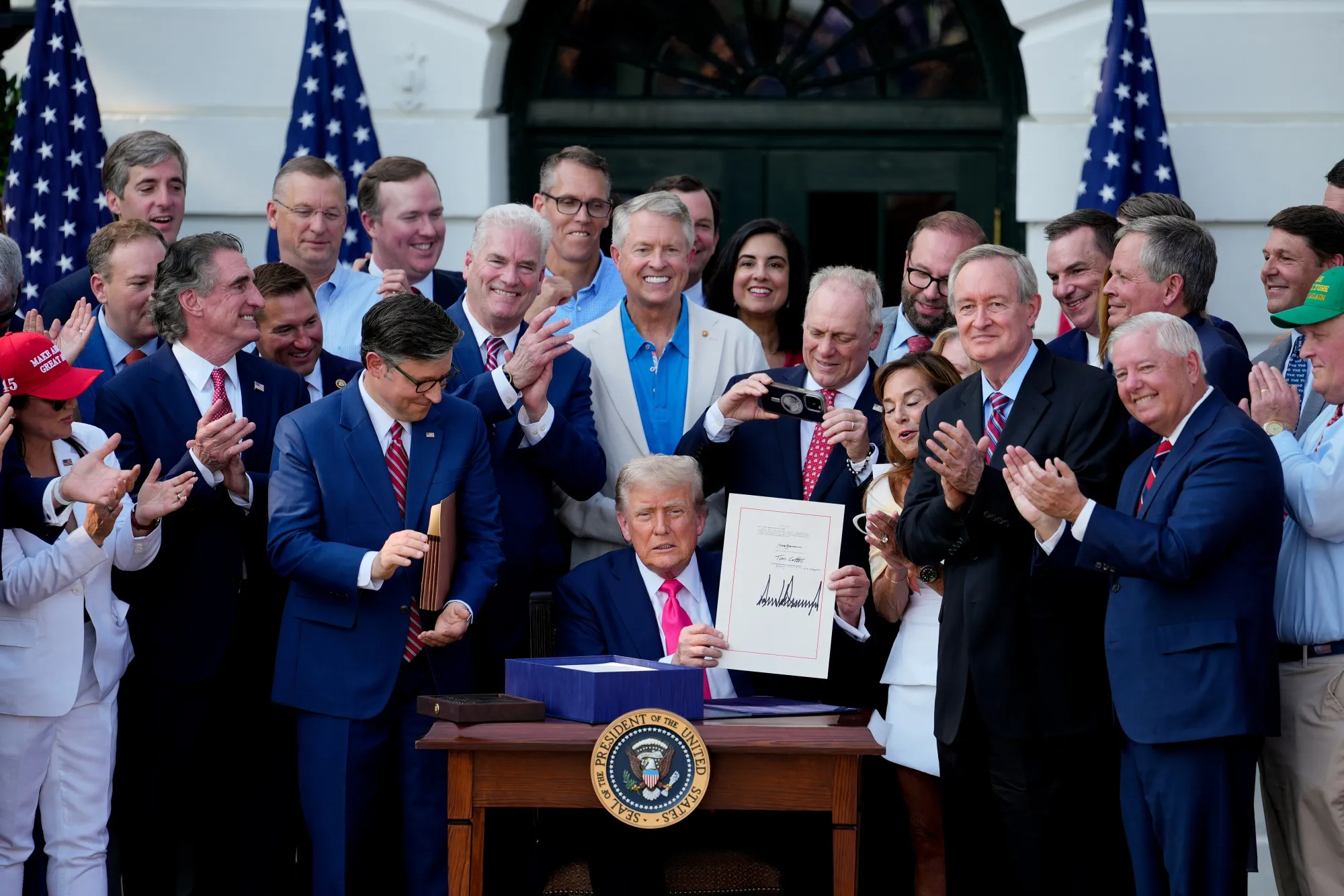 US President Donald Trump displays the signed bill during a ceremony for the One Big Beautiful Bill Act on the South Lawn of the White House on July 4, 2025.