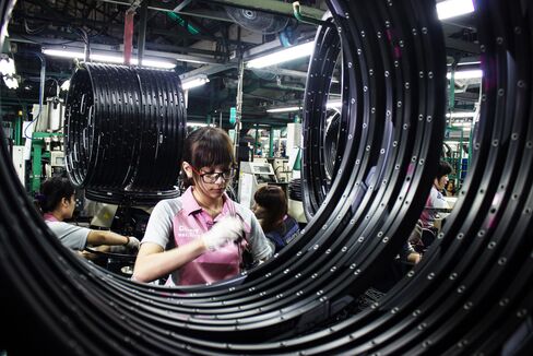 An employee assembles wires to a wheel frame of a bicycle at the Giant Bicycle manufacturing facility in Taichung.