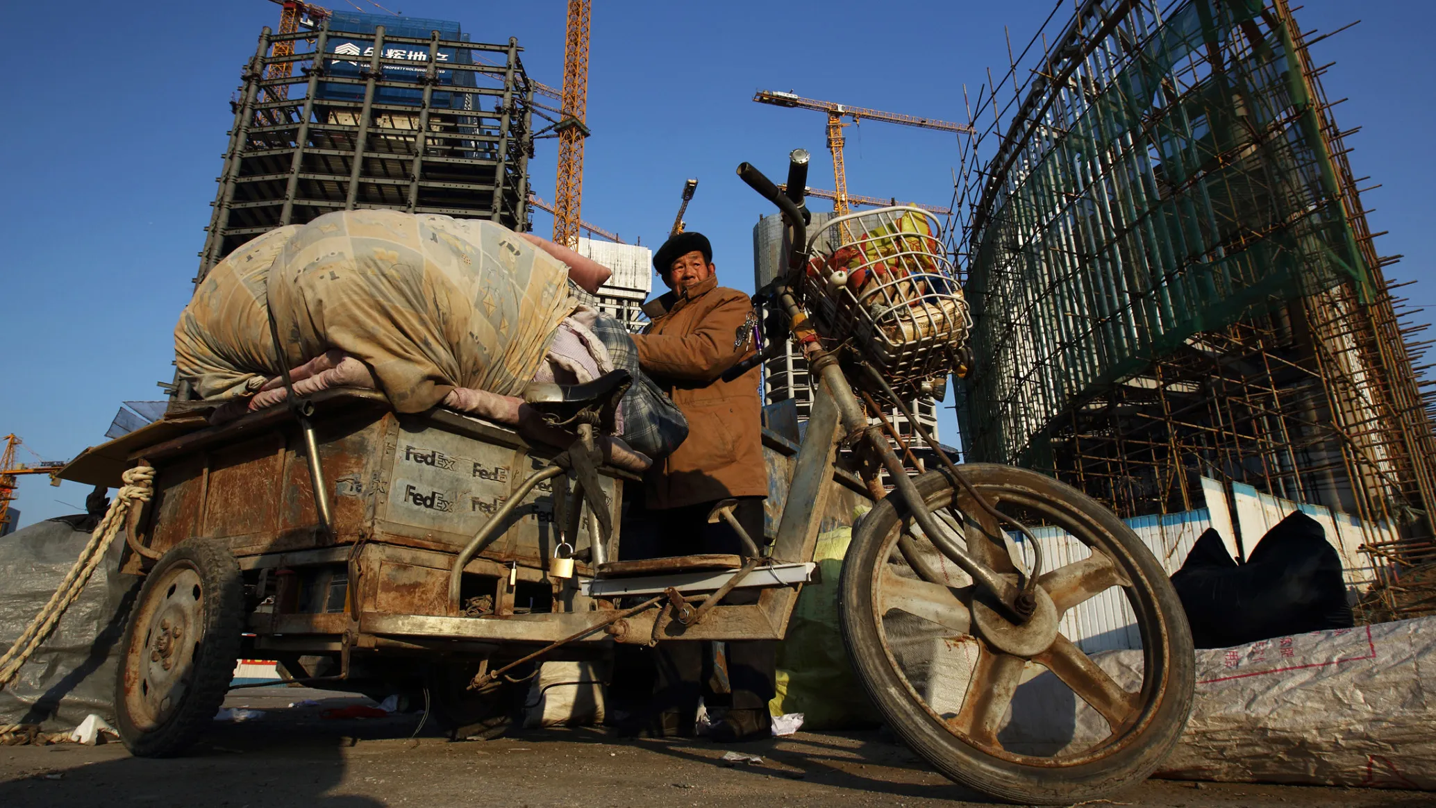A worker places collected waste on a tricycle at a commercial building construction site in Beijing.
