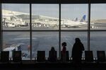 Travelers look out a window at LaGuardia Airport in New York.