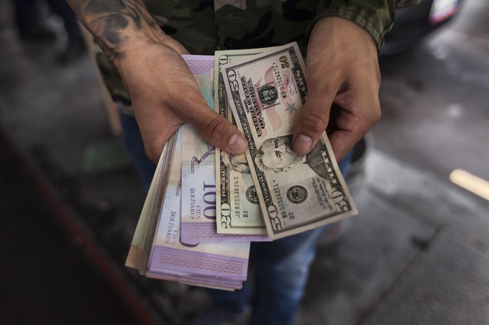 A person holds U.S. dollars and Venezuelan bolivares in Caracas.