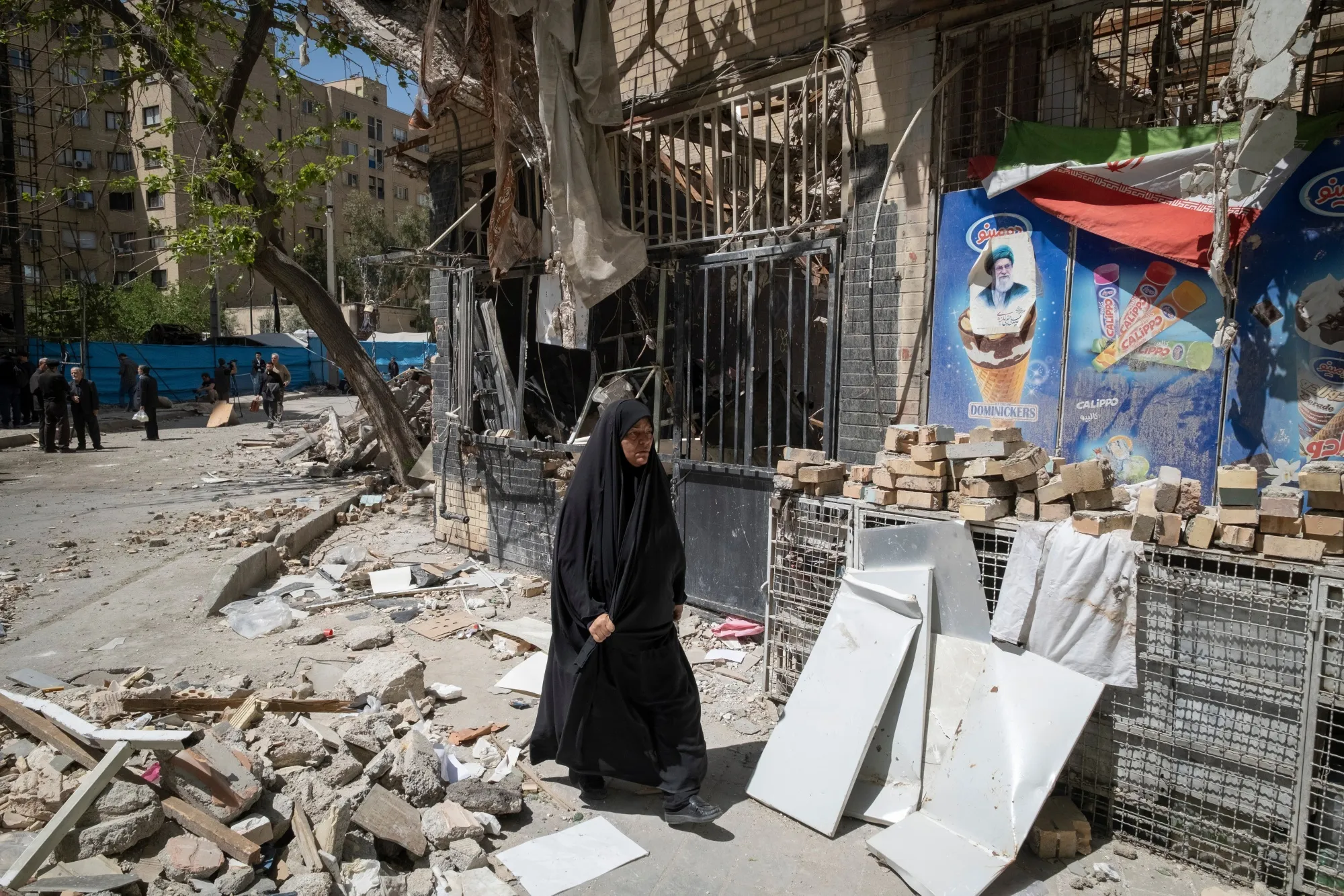 破壊されたスーパーマーケットの前を歩く女性（テヘラン南部、4月14日）