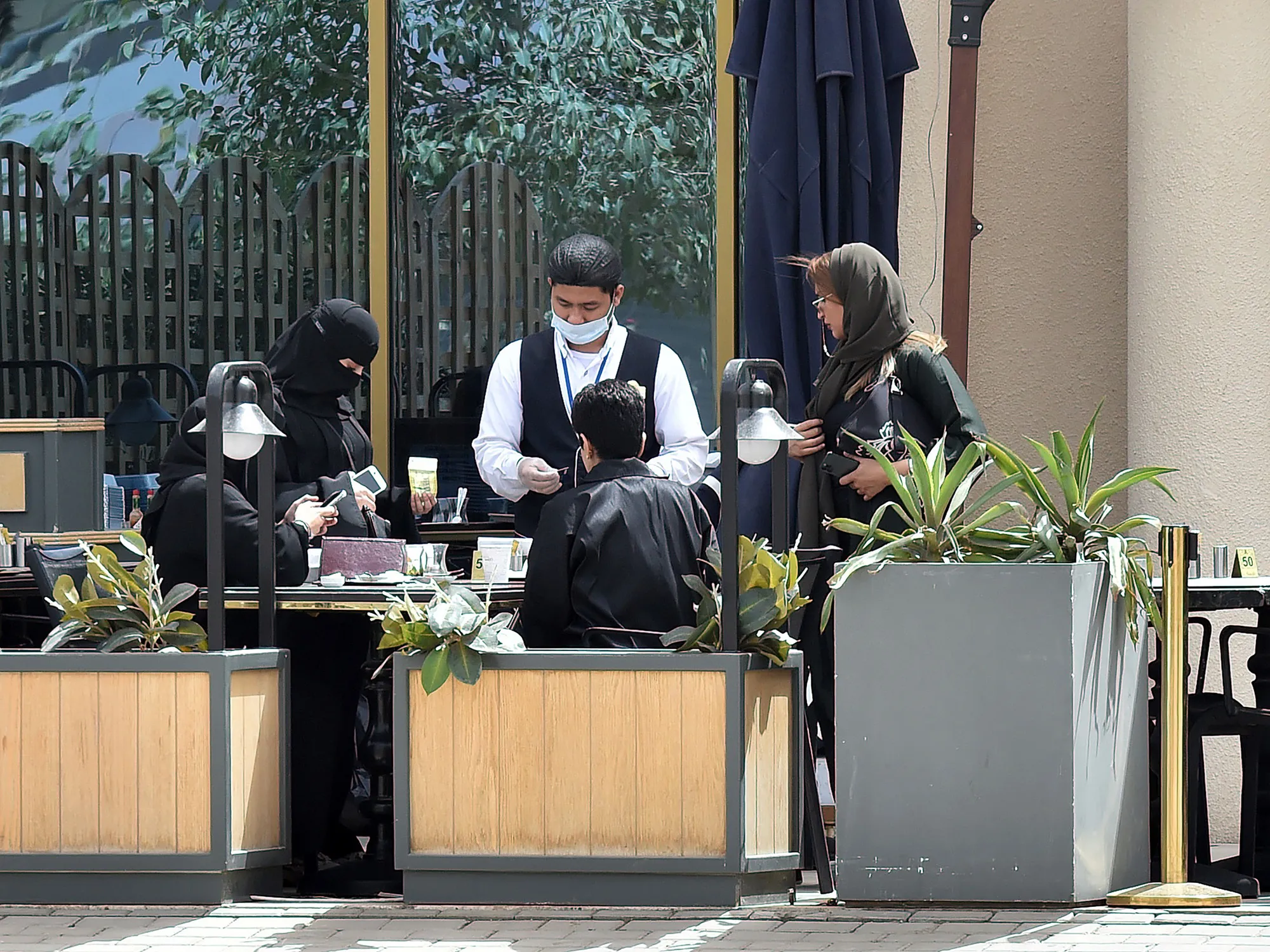 A waiter wearing a protective face mask serves a family in Riyadh