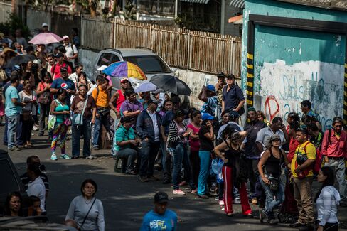 People wait in line outside of a grocery store in Caracas. Photographer: Meridith Kohut/Bloomberg