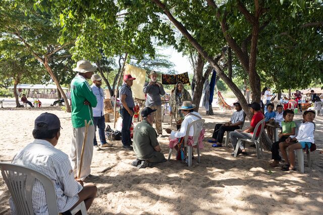 GEB executives and employees sit around a member of the Wayuu community, center right, who tells them about their culture and customs.